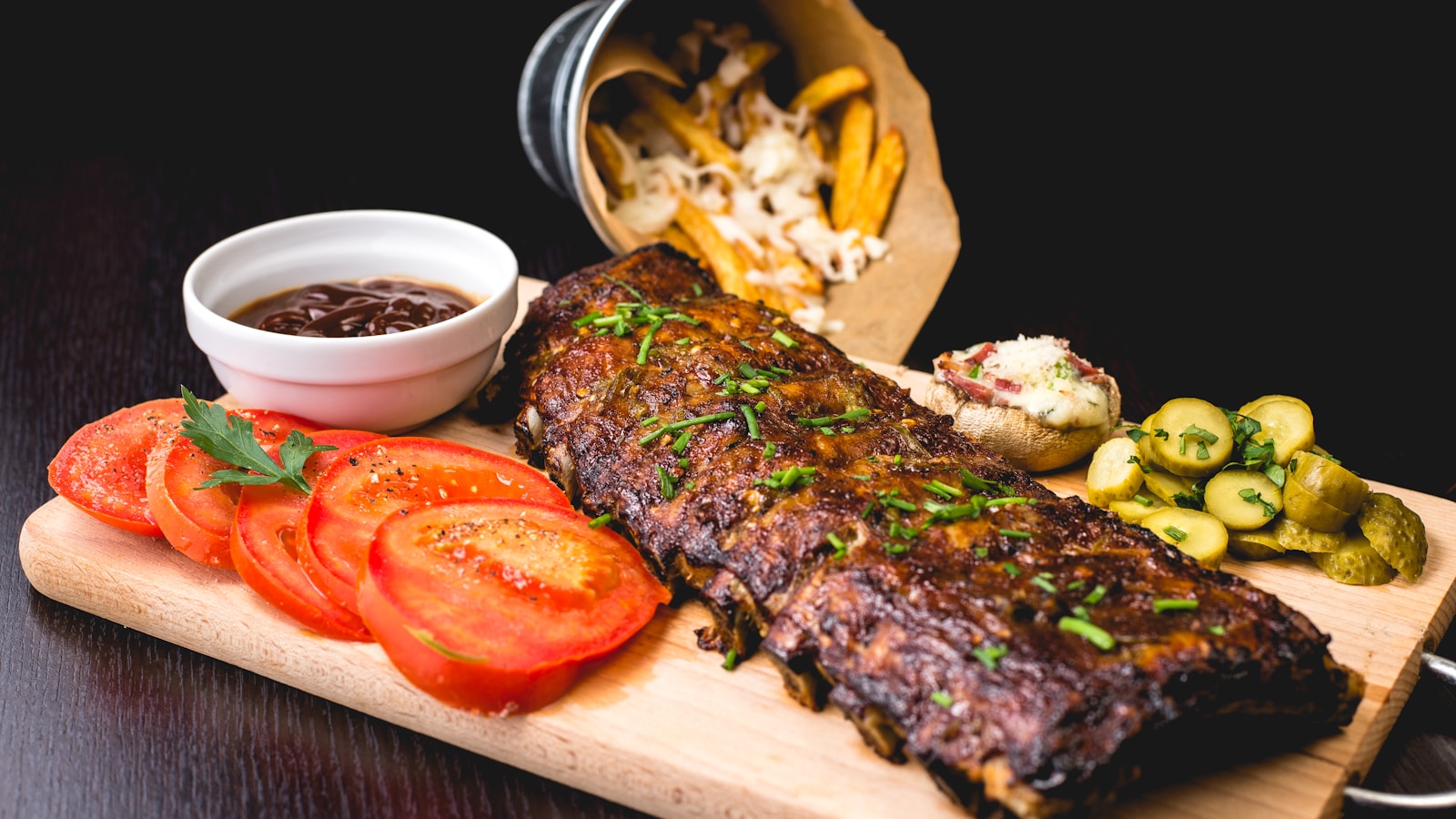 Shredded achiote pork in a clay dish with pickled red onions and lime wedges